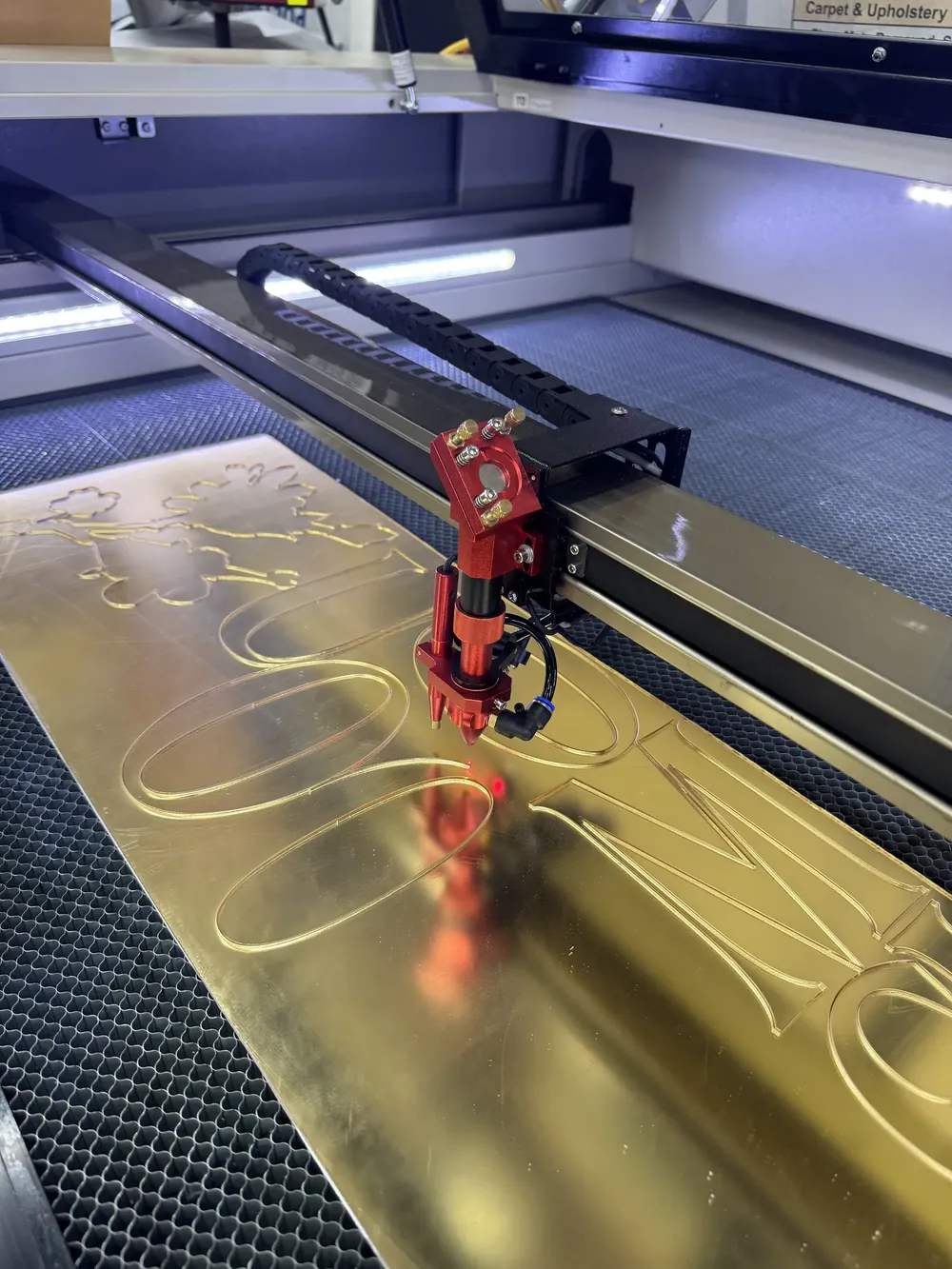 Laser cutter cutting gold acrylic letters in the shop